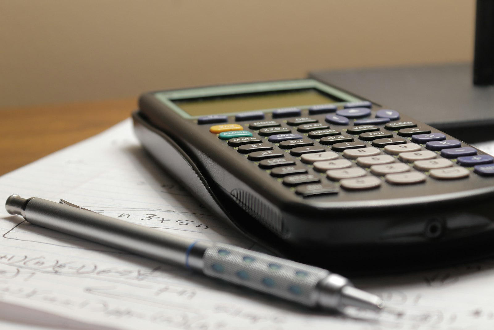 Foto real de uma calculadora e uma caneta sobre um papel, tentando organizar o negócio